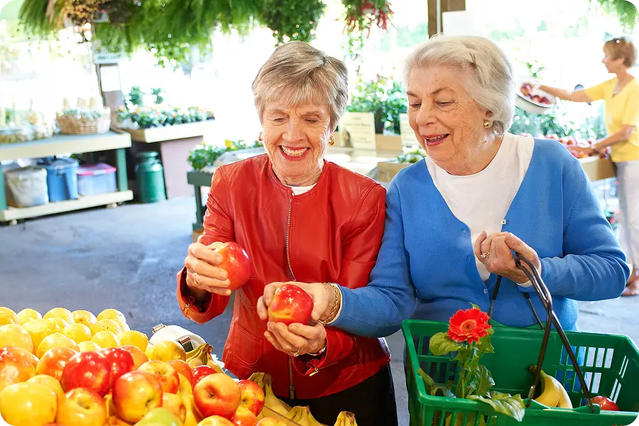 Two women browsing fresh produce together at an outdoor market