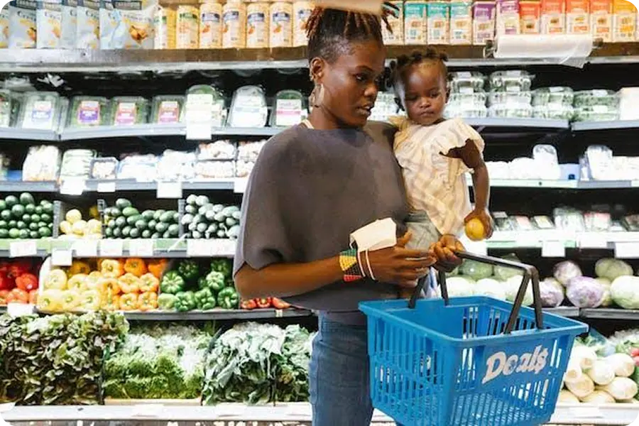 Mother shopping in the produce aisle with her toddler on her hip