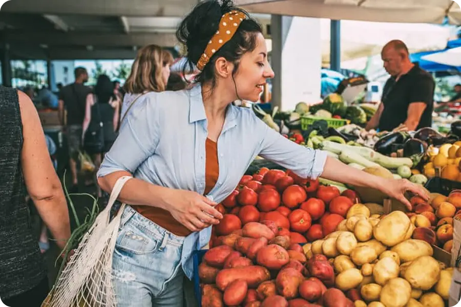 Woman selecting fresh vegetables at an outdoor farmers market